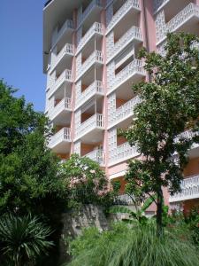 a pink apartment building with trees in front of it at Apartment Jadranka in Portorož