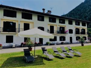 a group of chairs and an umbrella in front of a building at Casa Felicita in Ledro