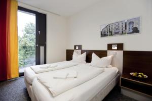 uma grande cama branca num quarto com uma janela em Jugendherberge Düsseldorf em Dusseldorf