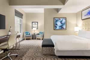 um quarto de hotel com uma cama, uma secretária e cadeiras em Magnolia Hotel Denver, a Tribute Portfolio Hotel em Denver