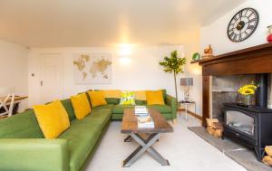 The Ilkley Hideaway في إلكلي: غرفة معيشة مع أريكة خضراء ومدفأة