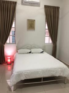 1 dormitorio con 1 cama blanca grande y 2 ventanas en Forest Reserve’s House, en Tampin