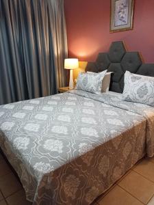1 dormitorio con 1 cama grande y edredón gris y blanco en Evangelia, en Karfas