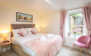 a bedroom with a bed and a pink chair at The Ilkley Hideaway in Ilkley