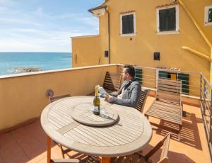 eine Frau, die an einem Tisch auf einem Balkon sitzt in der Unterkunft Terrazza cielo e mare in Imperia + 9 Fotos