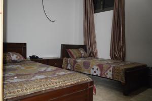 a bedroom with two beds and a window at Hotel Crown City in Muzaffarabad