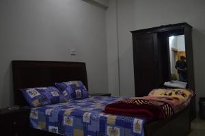 a bedroom with a bed with a blue comforter and a mirror at Hotel Crown City in Muzaffarabad