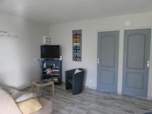 uma sala de estar com um sofá, uma televisão e uma porta em Gîte de la Grenouille em La Cambe