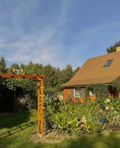 a garden with a wooden pergola next to a house at Ozierański Eden "Pod rzeźbami" 