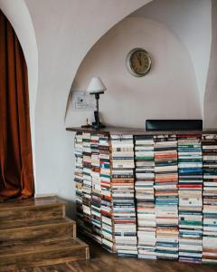 a large stack of books on a dresser with a clock at Rooms and Suites at Bookinn B&B in Vilnius