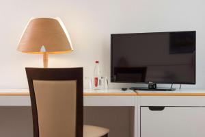 un bureau avec une télévision, une lampe et une chaise dans l'établissement Tryp by Wyndham Wuppertal, à Wuppertal