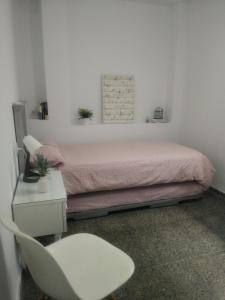 ein Schlafzimmer mit einem rosa Bett und einem weißen Stuhl in der Unterkunft Sevilla Macarena apartamento 3 dormitorios in Sevilla