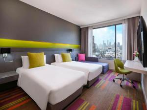 a hotel room with two beds and a window at Mercure Bangkok Siam in Bangkok