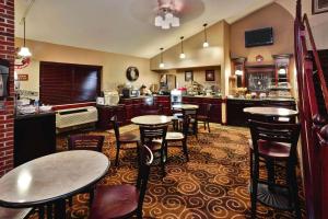 a restaurant with tables and chairs and a kitchen at AmericInn by Wyndham Beaver Dam in Beaver Dam