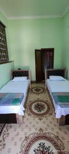 two beds in a room with two rugs at Sezam in Bukhara