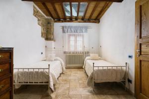 2 letti in una camera con pareti bianche e finestra di La Casetta Nel Borgo a Castelnuovo di Val di Cecina