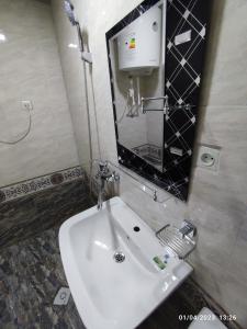 ein Badezimmer mit einem weißen Waschbecken und einem Spiegel in der Unterkunft Sezam in Buxoro