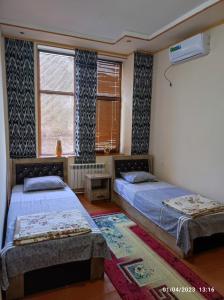 a bedroom with two beds and a window at Sezam in Bukhara