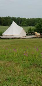 una gran tienda blanca en un campo con flores púrpuras en Camping La Petite Houmée, en Curzay-sur-Vonne