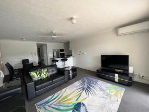 sala de estar con sofá y TV de pantalla plana en Cascade Gardens Apartments, en Gold Coast