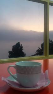 a coffee cup sitting on a plate in front of a window at Heavess Peak Hotel in Muzaffarabad