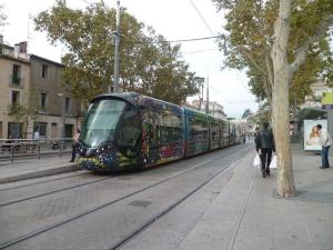 Artistic Loft, Downtown Montpellier, WIFI في مونبلييه: قطار طويل على شارع المدينة مع الناس يمشون