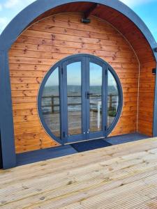 a wooden building with a large window on a beach at Spring Tide Cliff Top Glamping Pod with direct Sea Views in Birchington