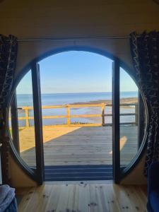 an open door to a deck with a view of the ocean at Spring Tide Cliff Top Glamping Pod with direct Sea Views in Birchington