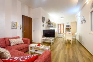 Lady Camollia Apartment في سيينا: غرفة معيشة بها كنبتين حمراء وتلفزيون