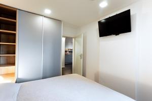 a bedroom with a white bed and a flat screen tv at Elegant 1-bedroom apartment near hill forest in Ljubljana