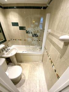 a bathroom with a toilet and a shower and a sink at The Brompton Hotel in London