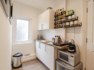 a small kitchen with white cabinets and a microwave at Sherwood Apartment in Margate