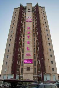 a tall building with a pink sign on it at Magic Suite Plus For Hotel Apartment in Kuwait