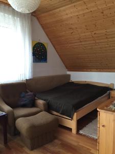 a bedroom with a bed and a couch and a window at Sirály Apartman in Balatonfůzfő
