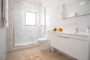 een witte badkamer met een douche, een toilet en een wastafel bij Olhos d'Água - Penthouse in Nazaré +33 foto's