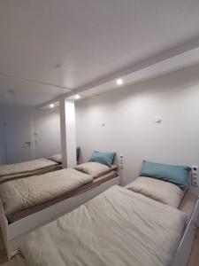 three beds in a room with white walls and blue pillows at Haus am Nymphensee2 in Brieselang +3 photos