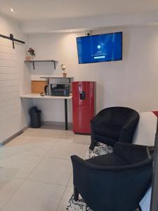 een woonkamer met een rode koelkast en een televisie bij Mint Guesthouse in Randfontein
