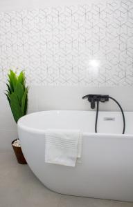 uma banheira branca na casa de banho com uma planta em Mint Guesthouse em Randfontein