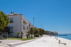 ein Gebäude auf einem Bürgersteig neben einem Wasserkörper in der Unterkunft Studio Apartment Jader in Zadar