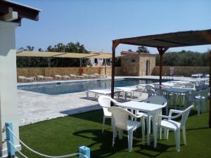 a patio with tables and chairs next to a pool at GOLDEN BEACH in Souvala