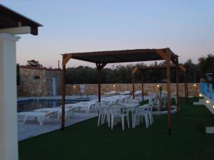 a group of white tables and chairs under a pavilion at GOLDEN BEACH in Souvala