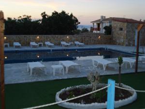 a swimming pool with tables and chairs next to a building at GOLDEN BEACH in Souvala