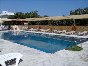 a swimming pool with chairs and umbrellas next to a building at GOLDEN BEACH in Souvala