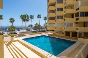 - une piscine en face d'un bâtiment avec des palmiers dans l'établissement Appartement en front de mer, à Marbella