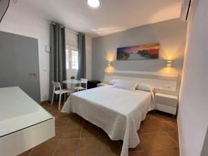 ein Schlafzimmer mit einem weißen Bett und einem Tisch in der Unterkunft Hostal Los Mellizos in Conil de la Frontera