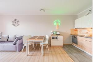 a kitchen and a living room with a table and a couch at Pool & Leisure Apartament Polanki Park in Kołobrzeg