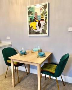 une table en bois avec deux chaises et une photo sur le mur dans l'établissement Lido's View, à Bristol