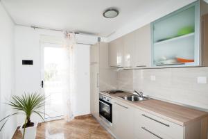 a kitchen with white cabinets and a sink at Apartments Toka in Petrcane