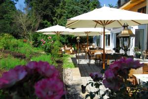 a patio with tables and umbrellas and flowers at Hotel Dreiflüssehof Gästehaus in Passau