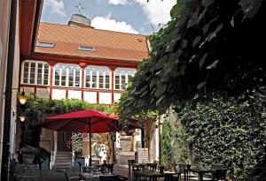 un patio con tavoli e ombrellone di fronte a un edificio di WEINreich, Gästezimmer & Weinstube a Freinsheim